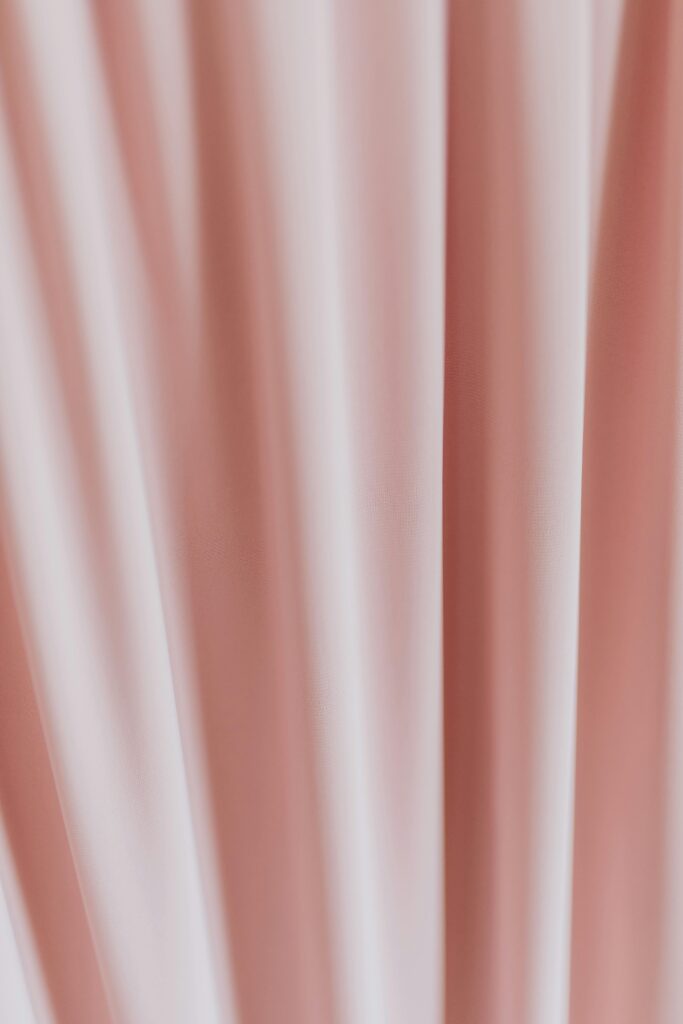 Close-up of a pink silk fabric creating an abstract draped texture, perfect for backgrounds.